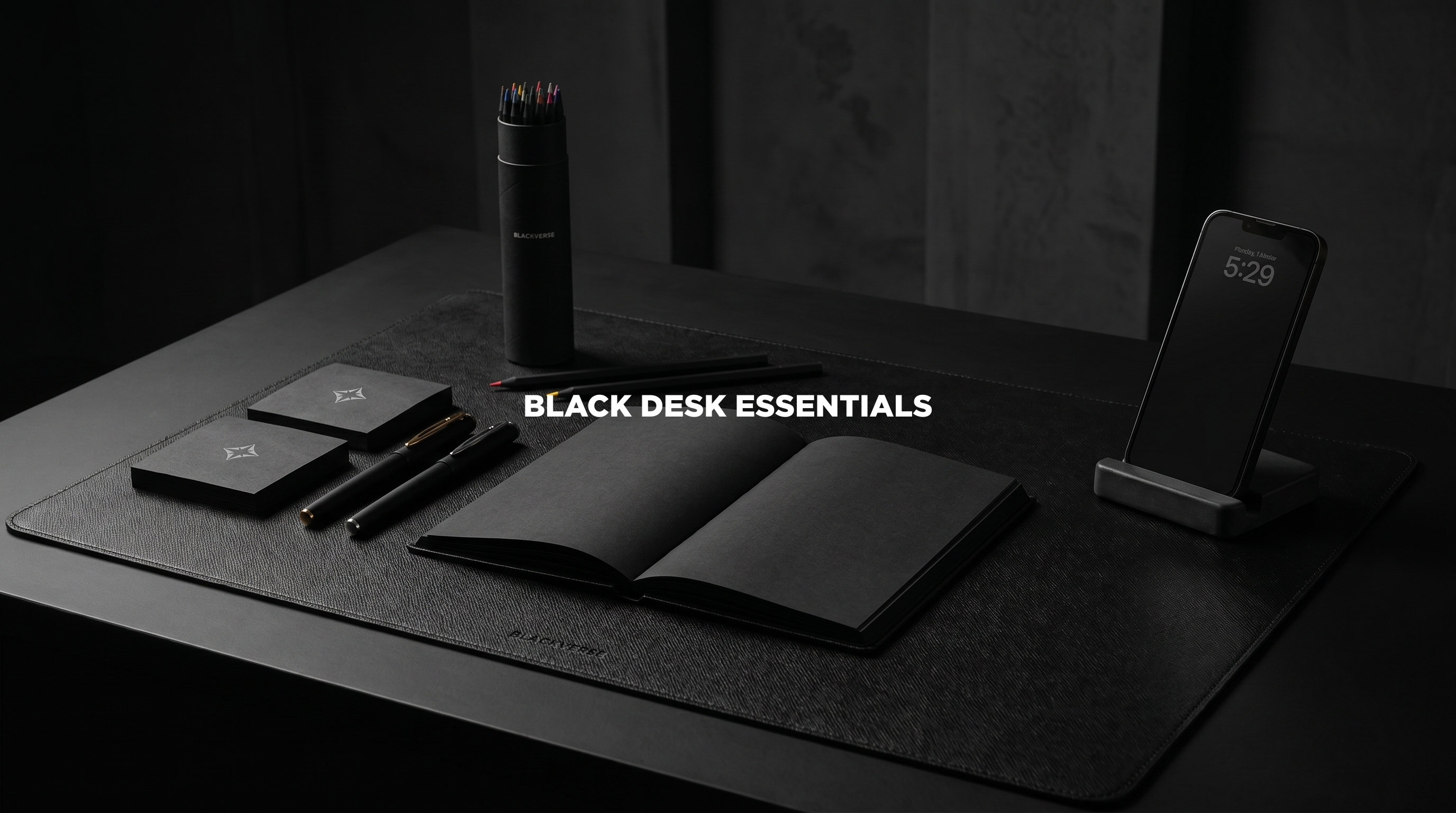 All-black desk setup with leather desk mat, notebook, concrete accessories, and black tumbler