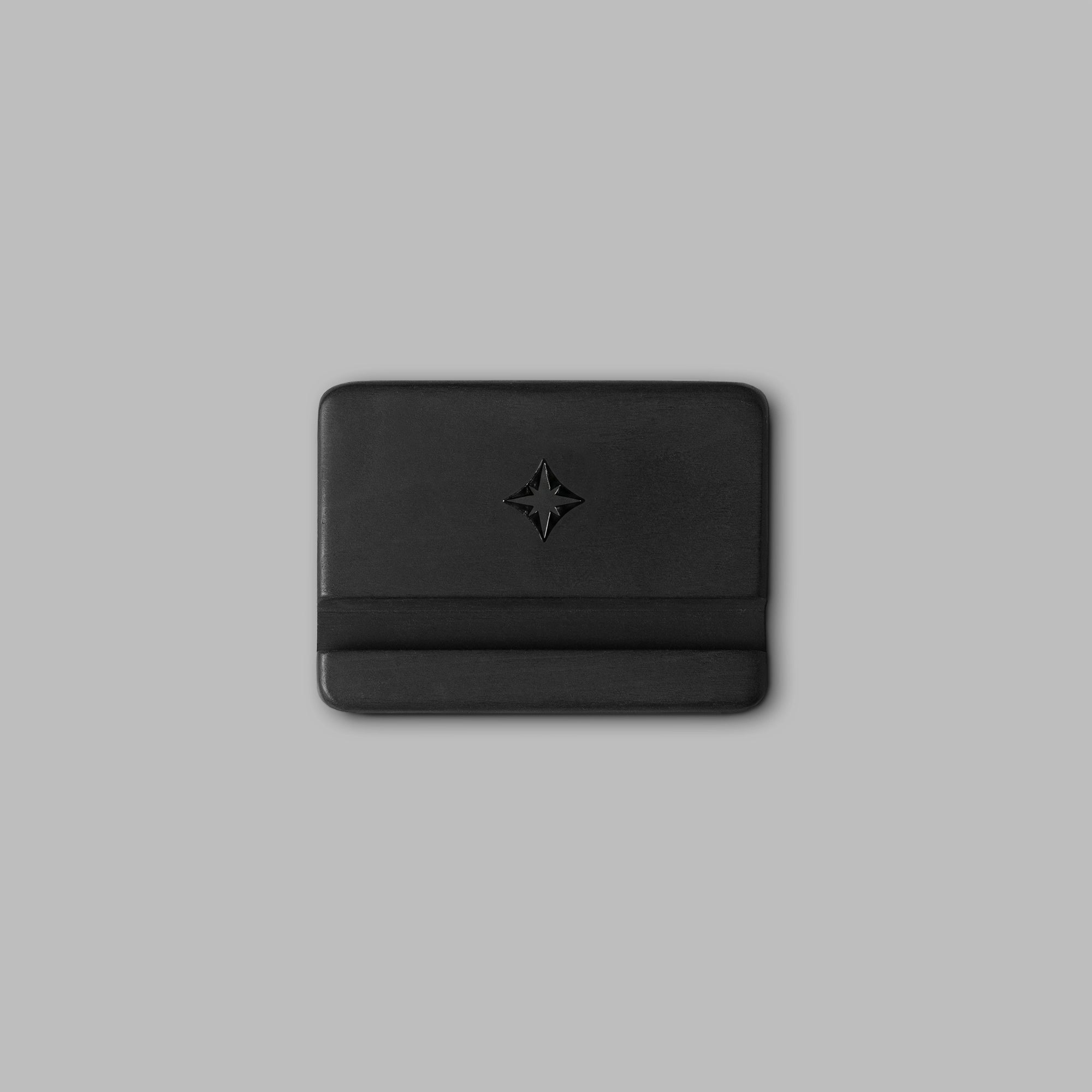 Black concrete phone holder cradling a phone, angled view — BLACKVERSE