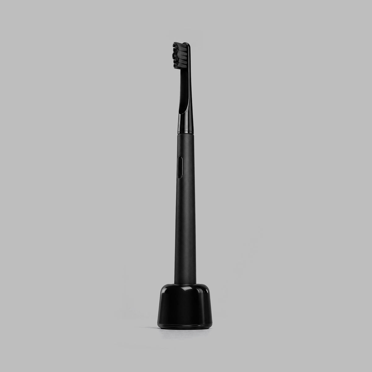 Matte-black sonic toothbrush standing upright on its charging base — BLACKVERSE