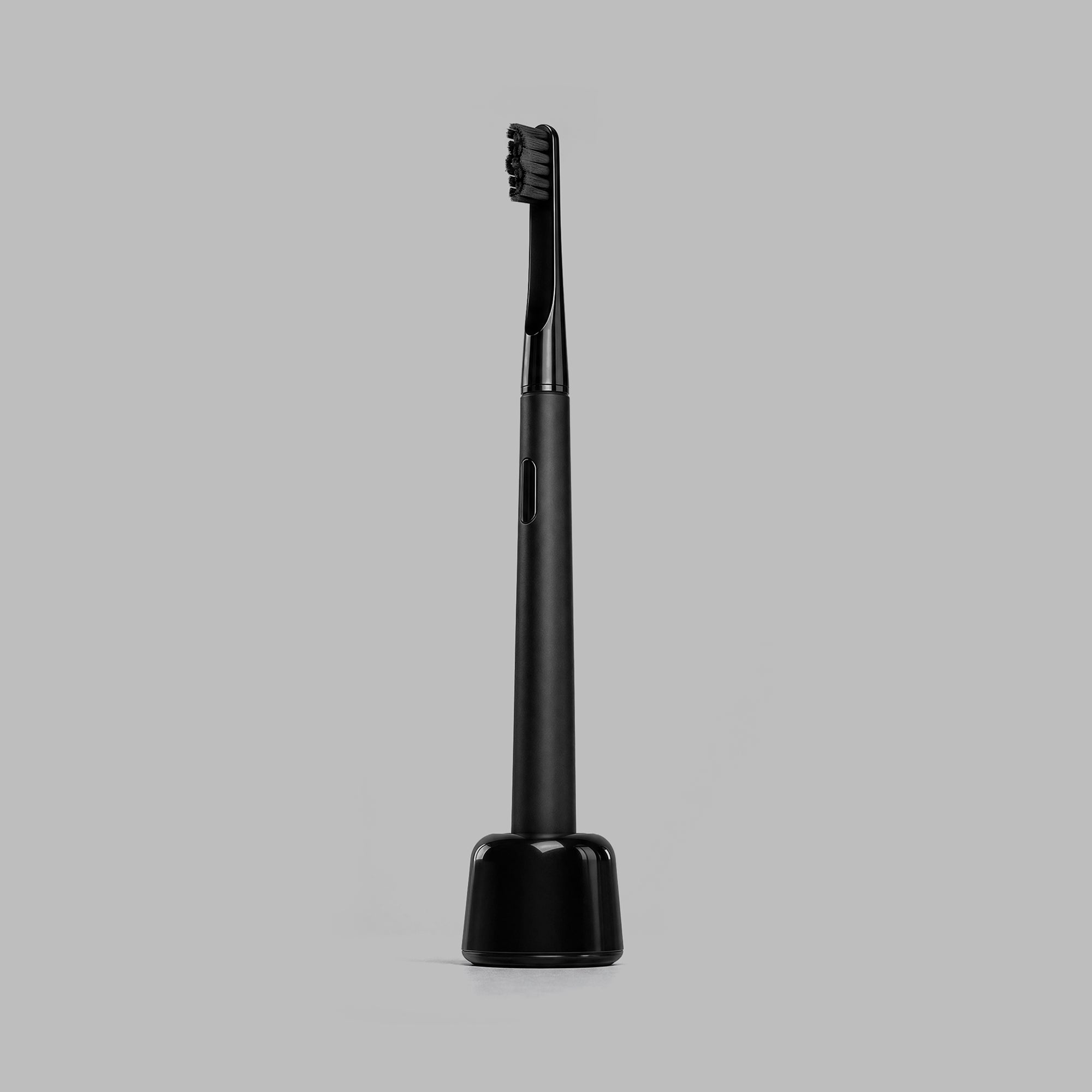 Matte-black sonic toothbrush standing upright on its charging base — BLACKVERSE